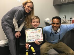 Peanut allergy oral immunotherapy treatment success story of Sullivan holding his certificate of completion with Dr. Chacko